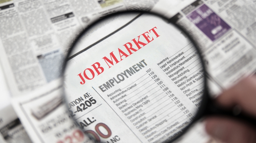 Magnifying glass over a newspaper classified section with Job Market text